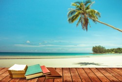 tree aged book and grunge paper on wooden platform beside tropical beach and blue sea on day noon light. background to school concept.
