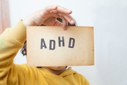 Child's hand, holding a vintage paper page with the abbreviation ADHD written on it