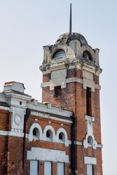 A beautiful old red brick building with a 19th century tower. Abandoned house with beautiful architecture in the city center. Vertical photo. 