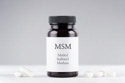 nutritional supplement msm, sulfur, methylsulfonylmethan bottle and capsules on gray