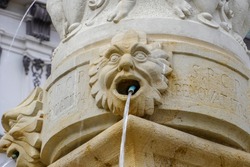 An old stone fountain, fresh drinking water flows from the mouth. High quality photo
