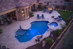 A high definition aerial view of a desert landscaped backyard with a pool, spa outdoor kitchen and fireplace.