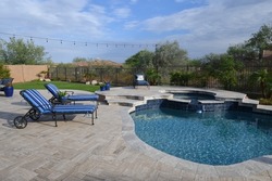 An Arizona back yard featuring a travertine tiled patio with a pool and spa.