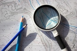 A magnifying glass and pencils on a planning basemap.
