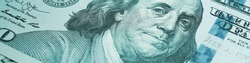 American paper money. A $100 bill with focus on eyes of Benjamin Franklin. US banknotes close-up. Business economy and the USA dollar. Light turquoise tinted banner or headline. Macro