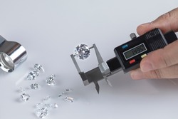 Closeup of diamonds at workplace of diamond dealer assessing quality and color of polished diamonds using various tools.