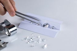 Closeup of diamonds at workplace of diamond dealer assessing quality and color of polished diamonds using various tools.
