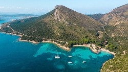 beach bay with clear water perfect for romantic vacation. Sailboats and catamarans anchor in the small bay. Paradise scuba divers. Drone aerial view, north Sardinia, Italy.