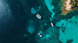 Secret beach with clear water perfect for romantic vacation. Sailboats and catamarans anchor in the small bay. Paradise scuba divers. Drone aerial view, north Sardinia, Italy.