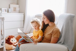 Mom reading book with baby boy toddler at home. Early age children education development. Mother and child kid spending time together. Family authentic candid lifestyle. 