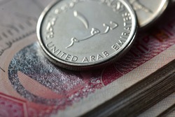 Extreme close up of one Dirham coin placed over hundred dirham note. Currency and coins of UAE.