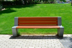 Front view of a bench in the public park. Modern looking bench beside the walkway in the lush green park
