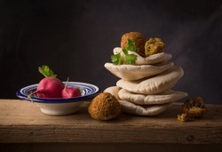 Falafel with Arabic pita bread and vegetables. A beautiful still life shot of Middle eastern cuisine. Delicious Falafil placed on heap of khaboos,  along with radish.
