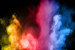 The explosion of multi colored powder. Beautiful rainbow color powder fly away. The cloud of glowing color powder on black background