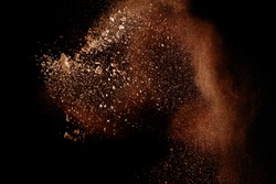 Freeze motion of brown dust explosion.Stopping the movement of brown powder. Explosive brown powder on black background.