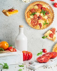 Tomato cheese tart - open pie on white background with basil and fresh tomatoes. Levitation trend food art concept, two crossed photo flats. Flying products. Cheese salty pastry.