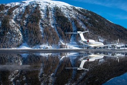 luxury business jet parked at Samedan airport. Successful business people use this airport to land at for their winter vaction in the Swiss alps. The water puddle is reflecting the plane and scenery.