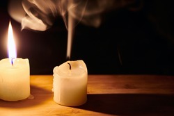 Burning and extinguished candle on wooden table. Smooth, white smoke from candle. Flame of the hope and memory. Standing out from crowd, exhausting or dying concept. Close up view with copy space.