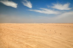Dry desert landscape. Hot lifeless sand of desert and blue sky in summer sunny day. Flat desert of Egypt. Travel and tourism concept.