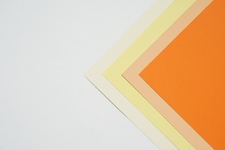 abstract background concept with stacking of color paper in geometric pattern, layers of blank orange paper and beige colour, yellow, cream colour paper on white background.