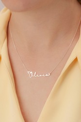 Name silver necklace on attractive female model. Woman wearing personalized necklace. Jewelry photo for e commerce, online sale, social media.