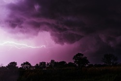 gloomy, mystical purple storm sky with lightning discharges and gloomy swirling clouds