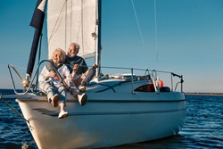 Sea trip. Happy beautiful senior family couple hugging and having fun while relaxing on a sail boat or yacht deck floating in a calm blue sea, they enjoying amazing sunset