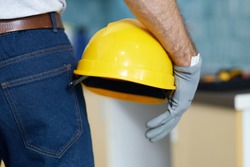 Close up shot of professional repairman holding a helmet while standing indoors