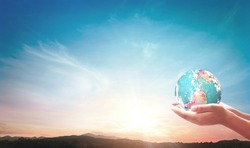 World environment day concept: Human hands holding earth globe on mountain sunset background. Elements of this image furnished by NASA
