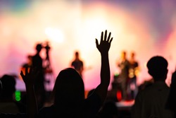 Background of Sunday service in church: Blurred silhouette woman raised hand to worship God