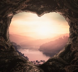 Inspire concept: Heart shape of cave on river and beautiful bright mountains sunset background