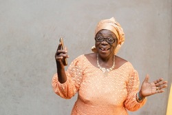 Cheerful african black mother holding up mobile phone whilst looking at camera