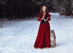 Beautiful girl in medieval dress with lynx in forest