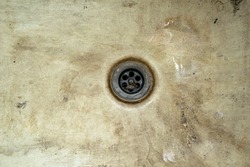 A drain hole in an old, dirty, battered sink. Contamination of the drain hole in an old unkempt bath
