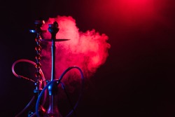 Hookah, shisha on a smoky black background with neon lighting and smoke. Place for your text