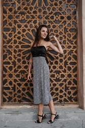 Caucasian young woman posing at a wooden door in Arabic style. Oriental style