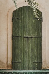 Green wooden door set into a brick building in Morocco