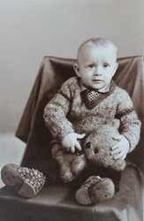 Vintage photo of little cute boy sitting in the chair with a bear (early1980's)