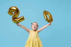 Little child girl is holding foil balloons in the form of numbers 20 twenty percent. The concept of discounts, sales and cashback. Blue studio background