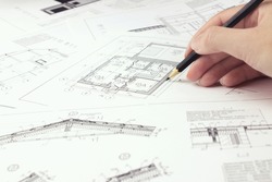 Designer are working on a new project blueprint Design at desk in office. Architects workplace - architectural project and hand with pencil. Architectural plans