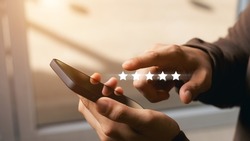 A male customer gives a five-star rating on their smartphone, satisfaction, customer service experience. Service Rating Reviews and Satisfaction Survey Concept.