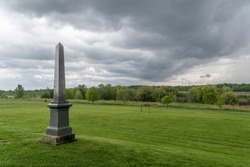 A lone gravestone stands tall at the edge of Salem United Church Cemetery overlooking a lush green field on a cloudy day in Pickering, Ontario.