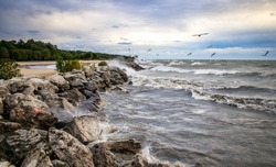 Large waves crashing against shoreline rocks on Lake Michigan in Milwaukee, Wisconsin in the morning with blue cloudy sky