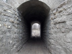 A short old stone tunnel under a railway bridge.          