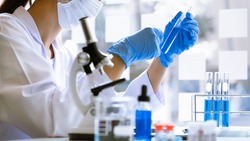 scientists researching in laboratory in white lab coat, gloves analysing, looking at test tubes sample, biotechnology concept.
