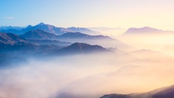 Mountain range with visible silhouettes through the morning colorful fog.