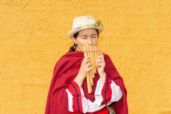 Latin American peasant woman with hat and red shawl playing the panpipe