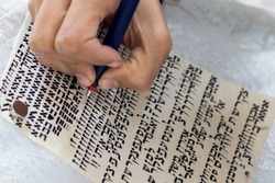 A writer practices decorating letters from a Torah scroll written on parchment in Hebrew, (for the editor - the Hebrew letters are random without meaning)