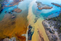 Acid rivers flowing from an industrial copper mine pollute the environment. Orange soil is contaminated with heavy metals from an industrial plant. Aerial view from drone
