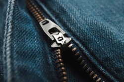 Metal zipper on denim texture, closeup or macro view. Fastener on jeans. 